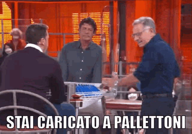 a group of men are sitting around a table with the words stai caricato a pallettoni on the bottom