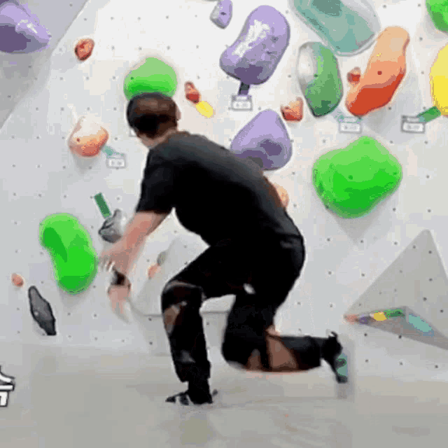 a man is kneeling down on a climbing wall with lots of rocks .