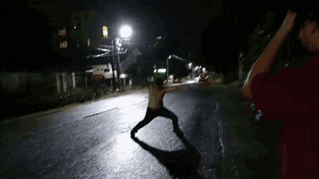 a man without a shirt is standing in the middle of a street at night