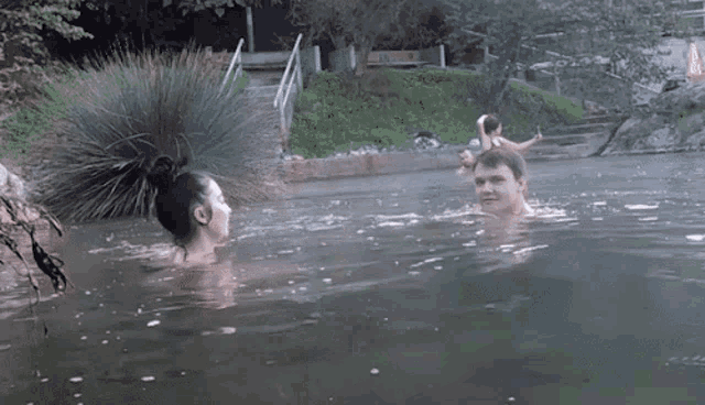 a man and a woman are swimming in a pool with a staircase in the background