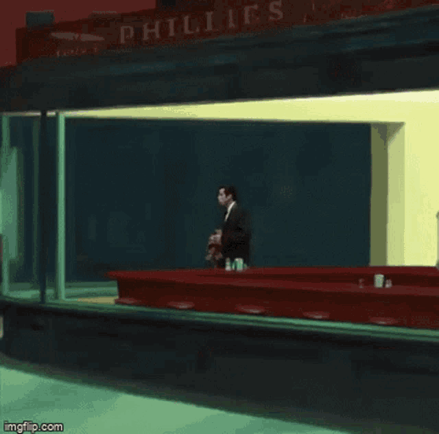 a man in a suit stands in front of a phillies restaurant