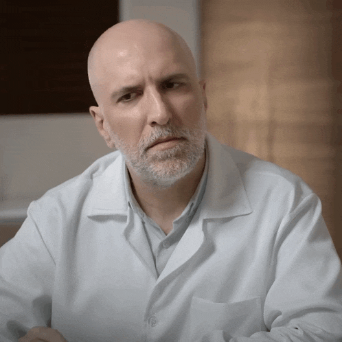 a bald man with a beard wears a lab coat