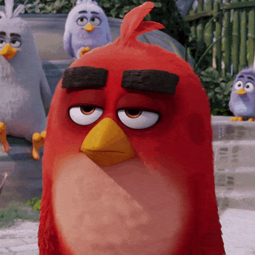 a red angry bird with a yellow beak is standing in front of a fence