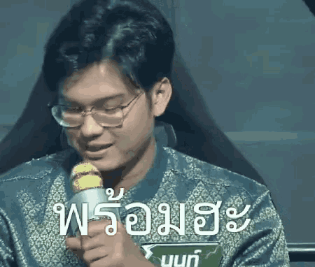 a man wearing glasses is holding a microphone in his hand and speaking into it .