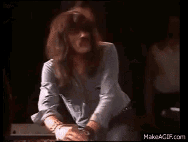 a woman is standing in front of a piano on a stage in a dark room .