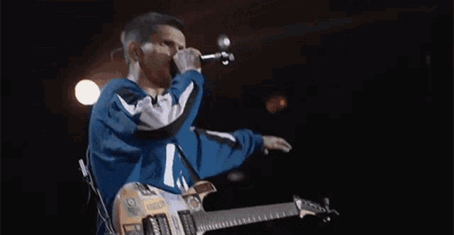a man is singing into a microphone while holding a guitar .