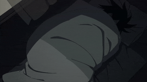 a person wrapped in a blanket is laying on a bed in the dark