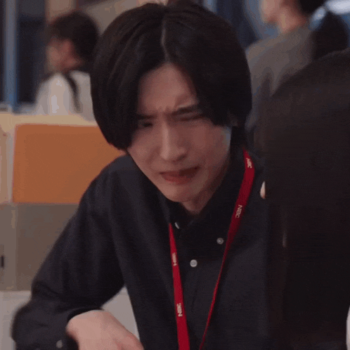 a man is making a funny face while sitting at a table with his hands together .