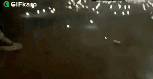 a person is standing in front of a firework display with a gifkaro logo in the corner .