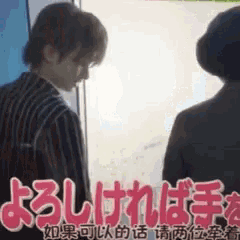 a man and woman are standing next to each other in front of a window with chinese writing on it .