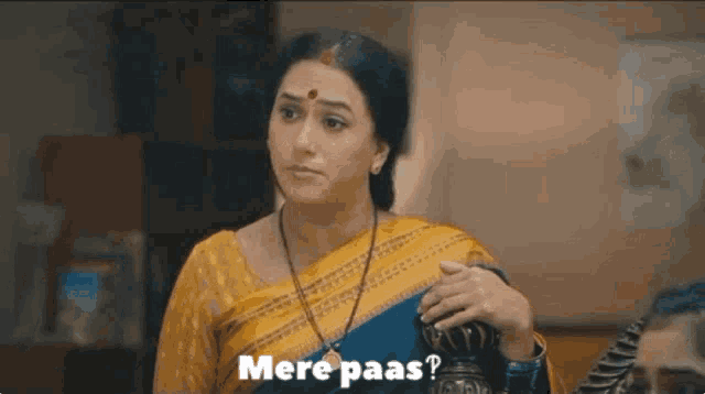 a woman in a yellow saree is holding a purse and says mere paas .