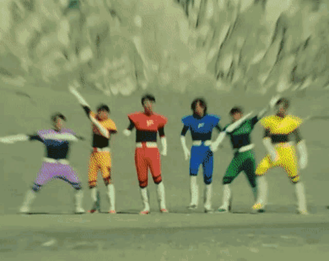 a group of power rangers are standing in the desert with rainbow colored lights coming out of their hands