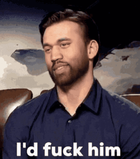 a man with a beard is sitting in a chair with the words `` i 'd fuck him '' written on his face .
