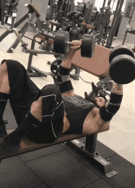 a man is lifting dumbbells on a bench in a gym wearing a black shirt that says ' power '