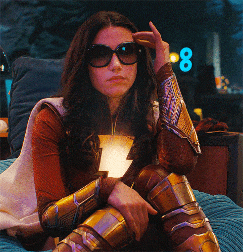 a woman in a superhero costume is sitting on a bed with her hand on her forehead