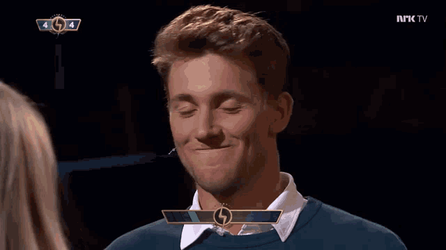 a man is smiling in front of a screen that says nrk tv on it