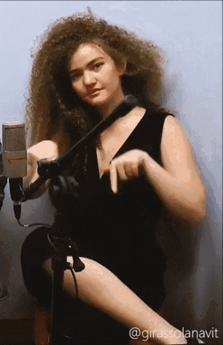 a woman in a black dress is sitting in front of a microphone with the hashtag @girassolanavit