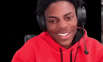 a young man wearing headphones and a red hoodie is smiling .