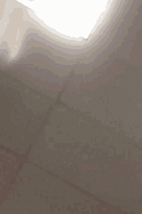 a close up of a person 's hand reaching up towards a light on the ceiling .