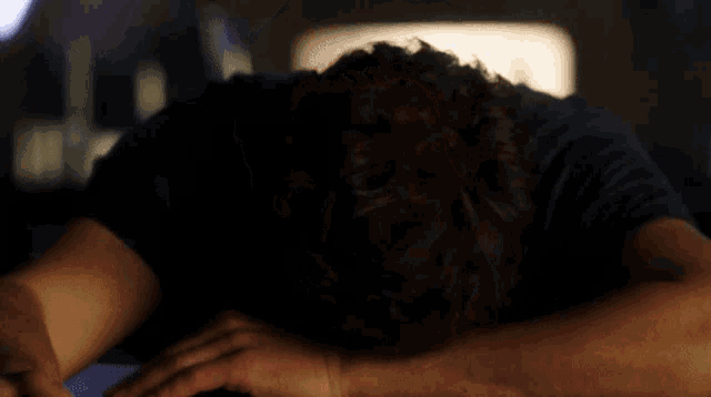 a man with a beard is laying down with his head resting on his arms