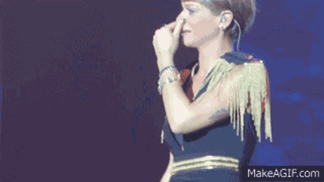 a woman singing on a stage with makeagif.com written below her