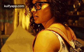 a woman wearing glasses and a backpack is looking over her shoulder at the camera .