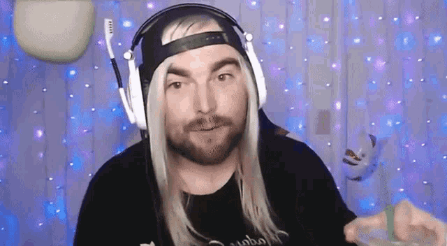 a man with long blonde hair and a beard wears headphones