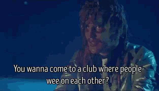a man in a metallic jacket is talking to another man in a club .