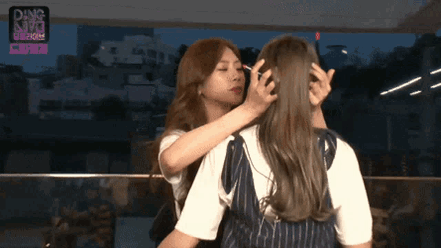 two women are kissing in front of a sign that says ding