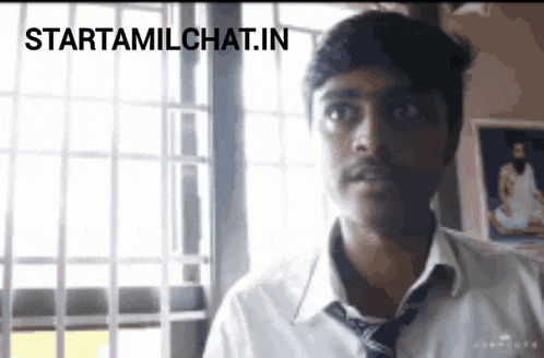 a man in a white shirt and tie is standing in front of a window with the words starttamilchat.in written below him