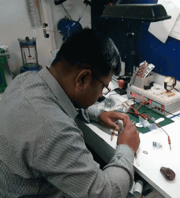 a man in a striped shirt is working on a device that says ' a ' on it