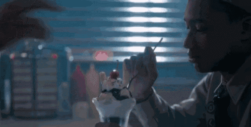 a man is eating an ice cream sundae with a cherry on top in a diner .