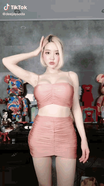 a woman in a pink dress is standing in front of a table filled with stuffed animals ..