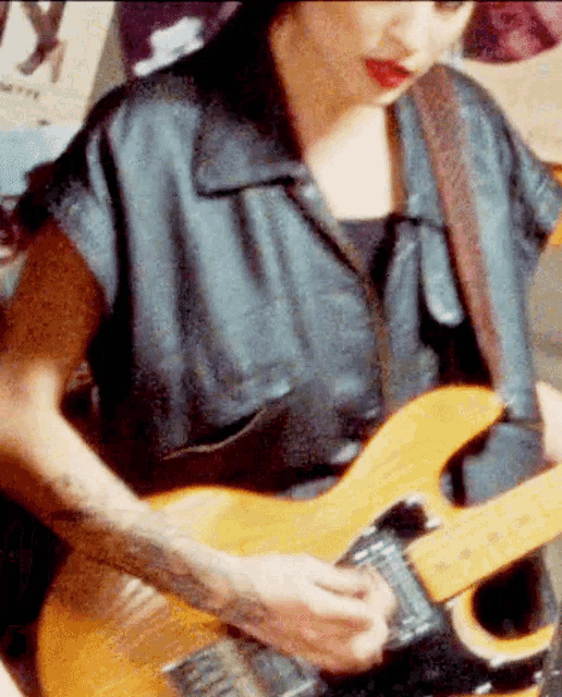 a woman in a black shirt is playing a guitar in front of a poster that says ' i love you '