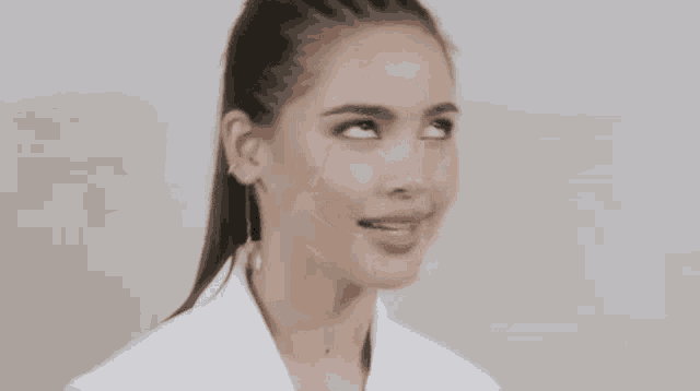 a woman is wearing a white shirt and a ponytail .