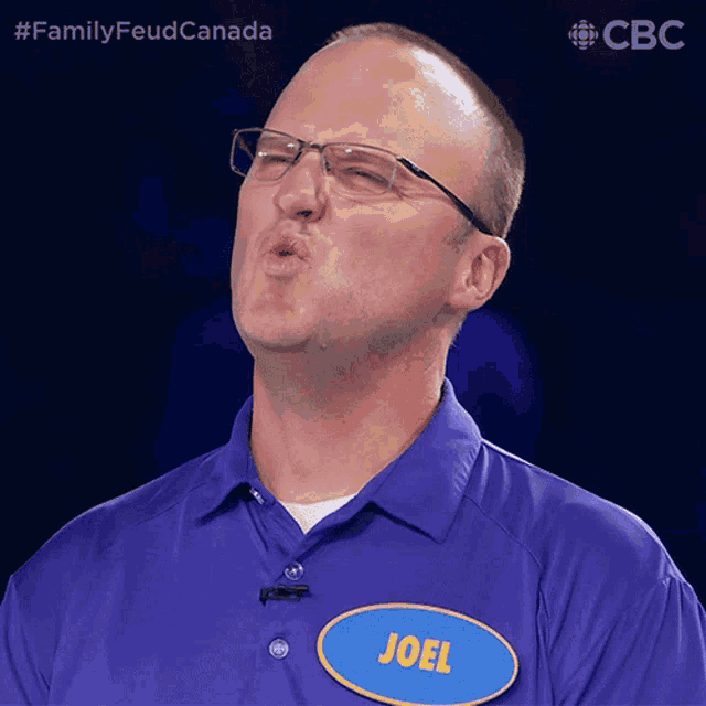 a man wearing glasses and a blue shirt with a name tag that says joel