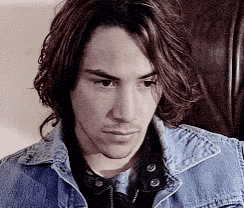 a man with long hair is wearing a denim jacket and a black shirt .