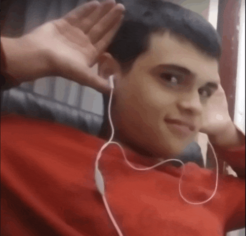 a young man wearing headphones and a red shirt is waving his hand