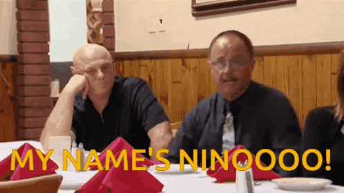 two men sitting at a table with the words my name 's ninoooo written in yellow letters