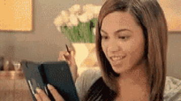 a woman is smiling while looking at a tablet computer .