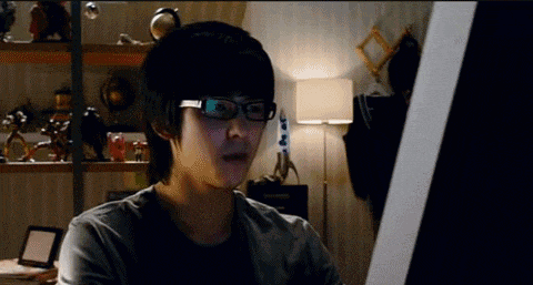 a man wearing glasses is looking at a computer monitor