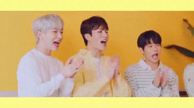 three young men are sitting next to each other laughing and clapping .