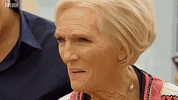 a close up of a woman 's face with wrinkles and a necklace .
