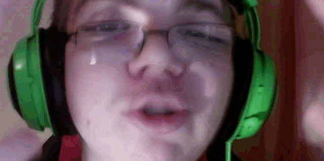 a boy wearing green headphones and glasses is crying .