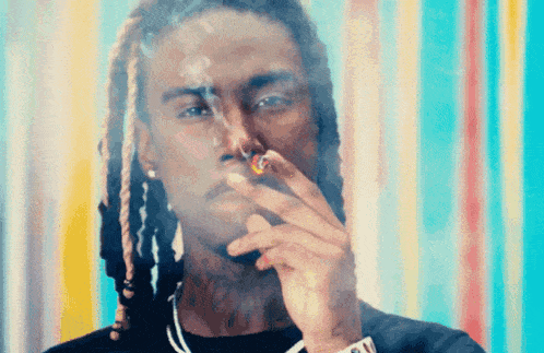 a young man with dreadlocks is smoking a cigarette