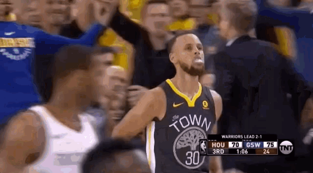 a basketball player in a golden state warriors jersey stands in front of a crowd .