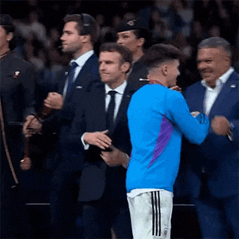 a man in a blue shirt is hugging a man in a suit .