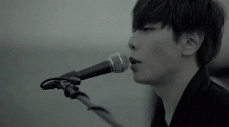 a black and white photo of a man singing into a microphone .