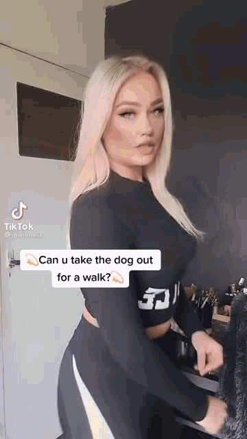 a woman in a black top and black pants is standing in front of a door and talking to a dog .