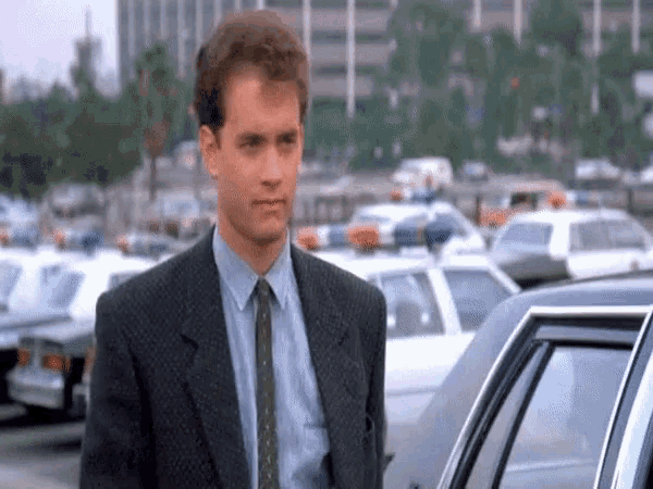 a man in a suit and tie is standing in front of a police car